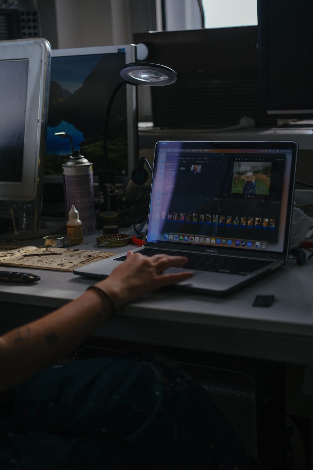 Hands on a laptop keyboard during video editing in a dim studio