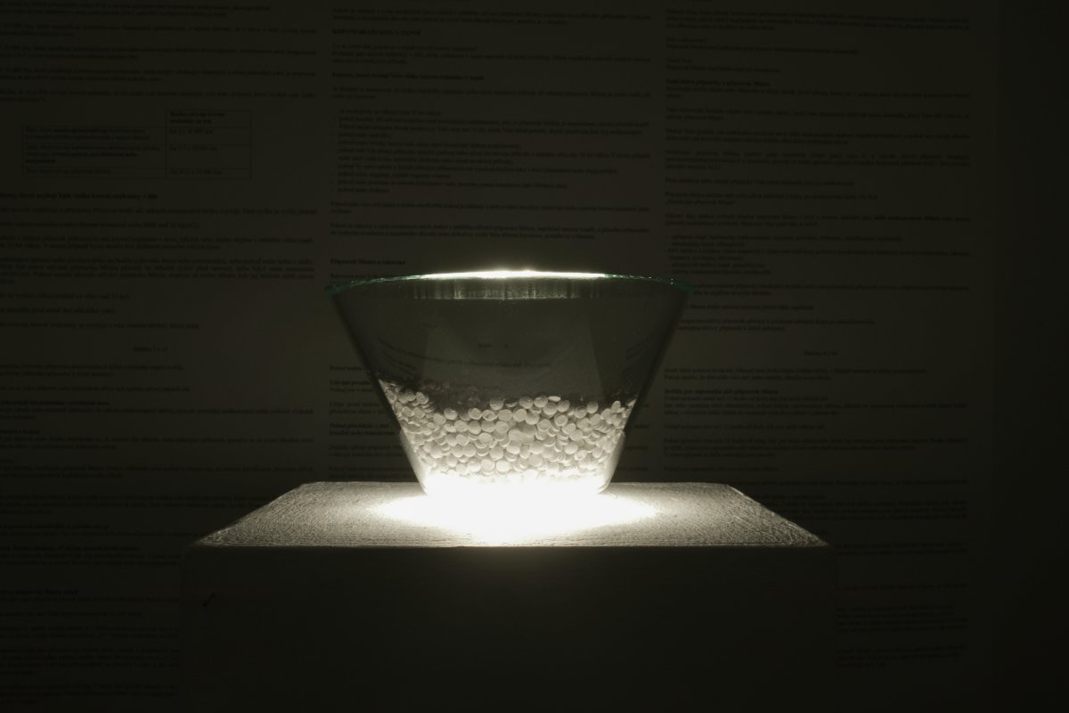 Glass bowl filled with pills, lit from below in a dark room