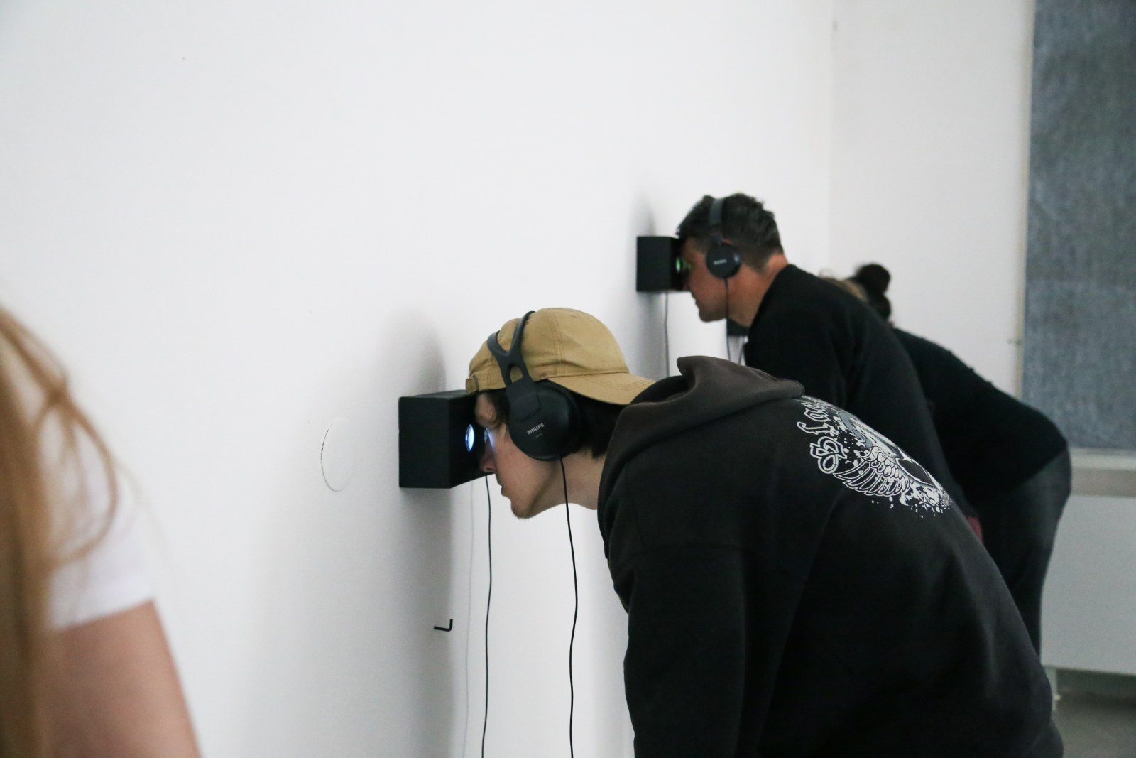 Visitors listening with headphones at a gallery wall