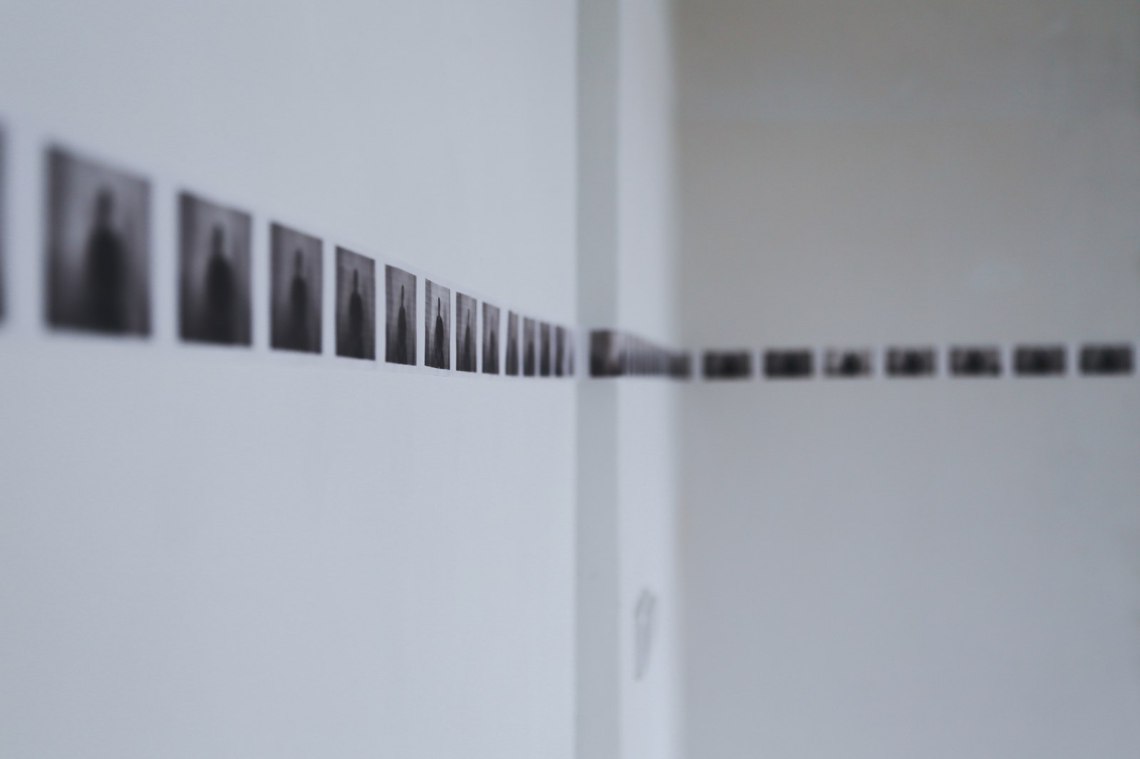 Row of small photographs along a white wall