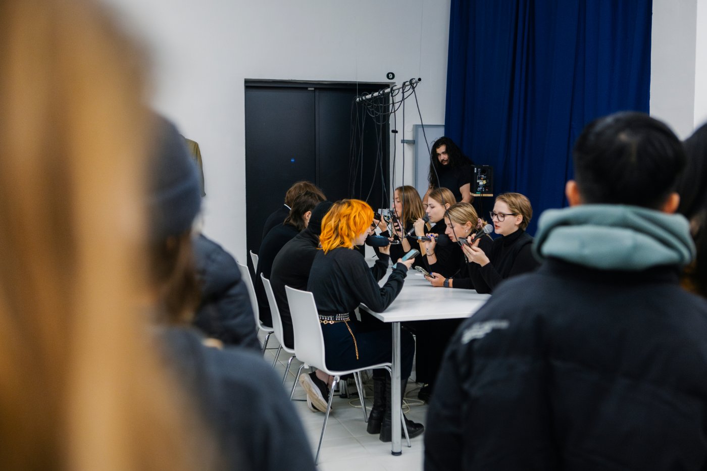 Performers seated around a table in a gallery