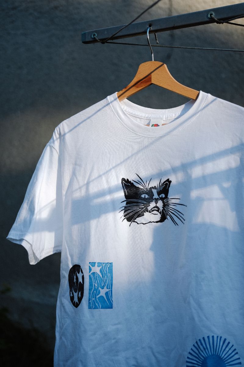 White T-shirt with a cat print on a hanger