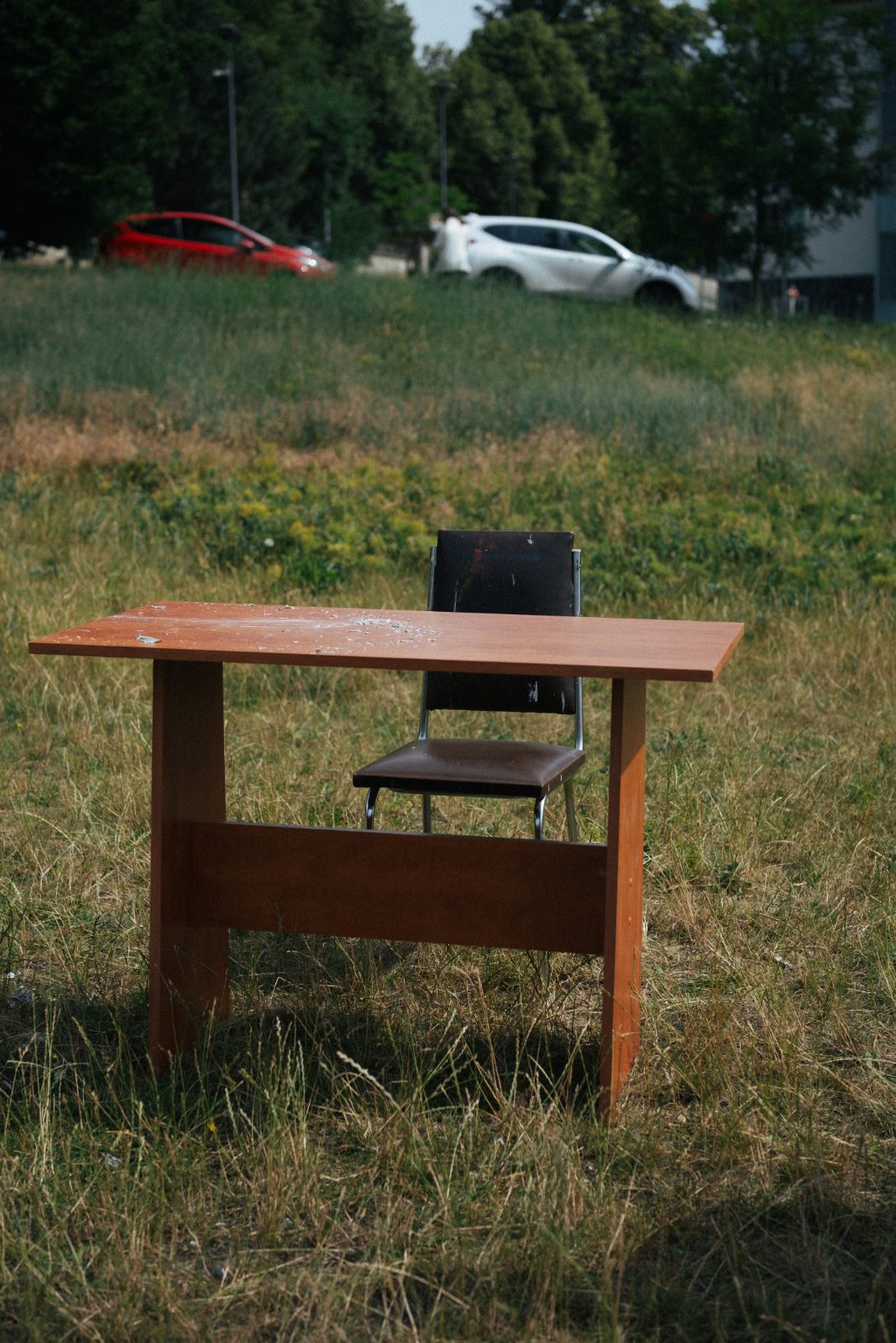 An empty wooden table and chair standing in tall grass