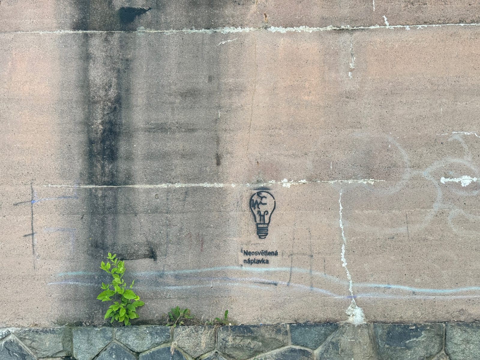 Small painted symbol and slogan on a concrete wall
