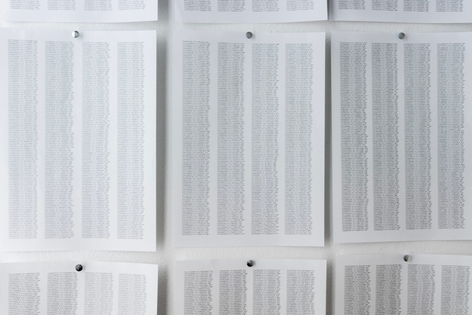 Grid of printed sheets of text pinned to the wall