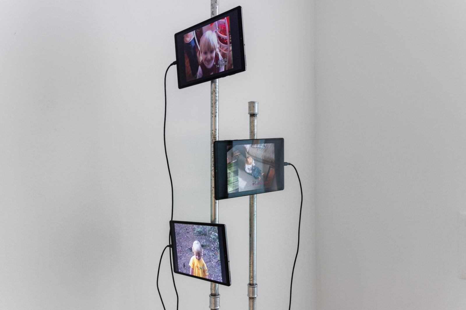 Tablets on a metal pole playing childhood VHS recordings