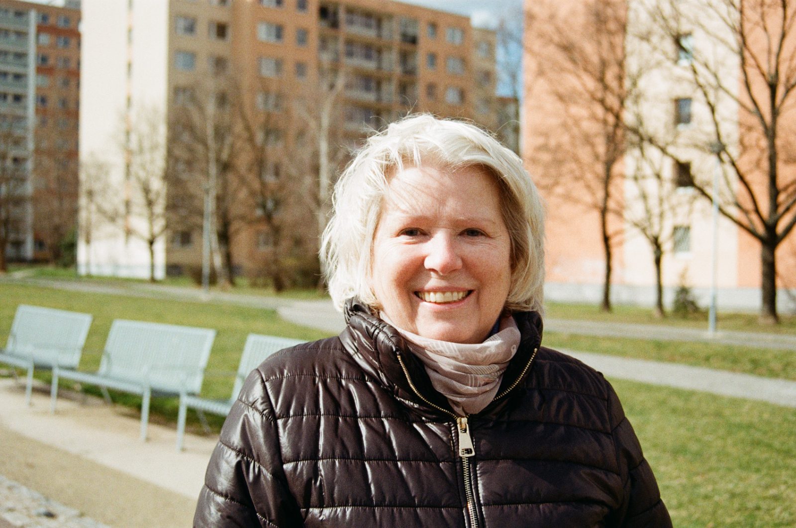 Smiling woman with white hair in front of panel buildings