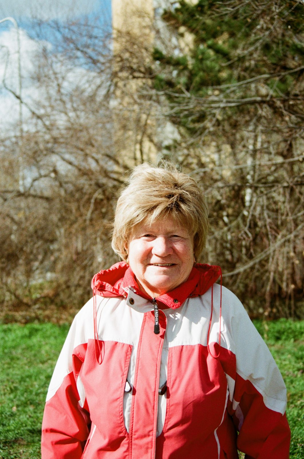 Woman in a red and white jacket on a sunny lawn