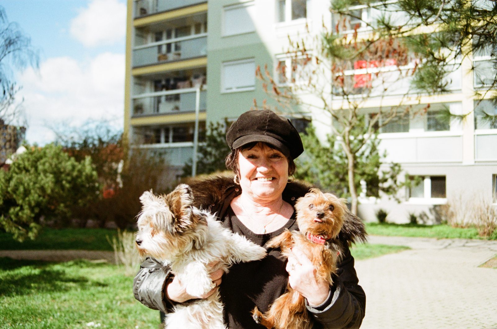 Woman holding two small dogs outside a housing block