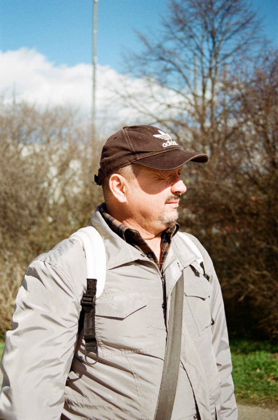 Man in a cap and grey jacket among bare trees