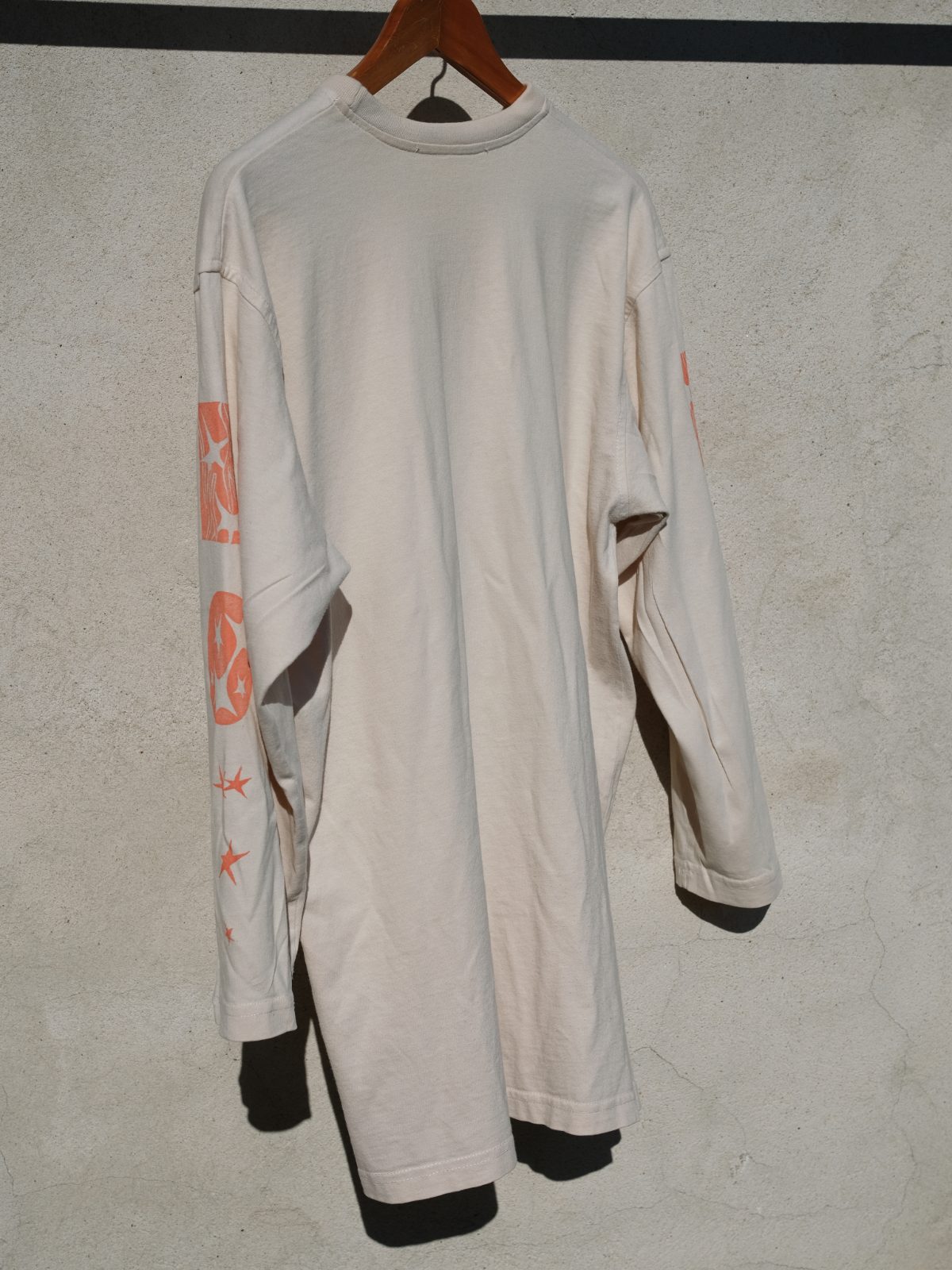 Side view of the cream long-sleeve shirt showing the printed sleeve