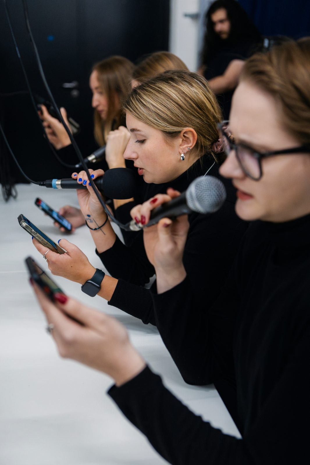 Hands holding phones and microphones during the performance